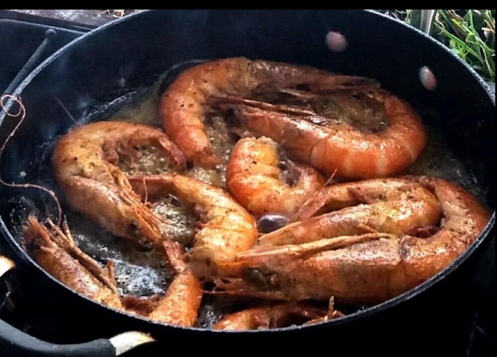 Camarones grandes dorándose en una cazuela con mantequilla