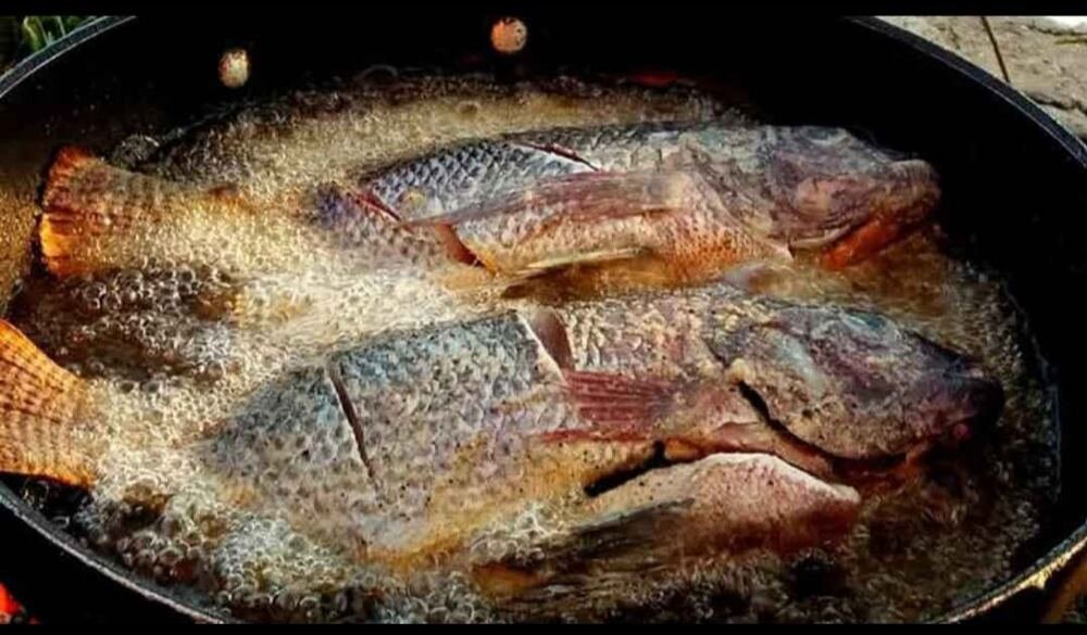 Pescados enteros friéndose en una cazuela de aceite caliente